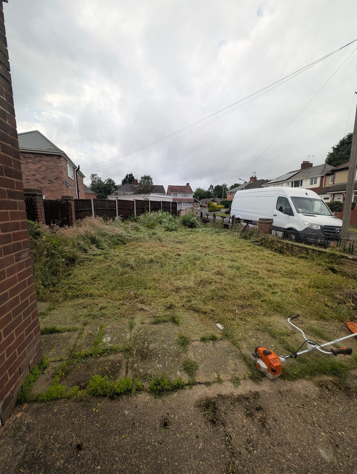 Garden part-way through, with the strimmer on the freshly cut grass
